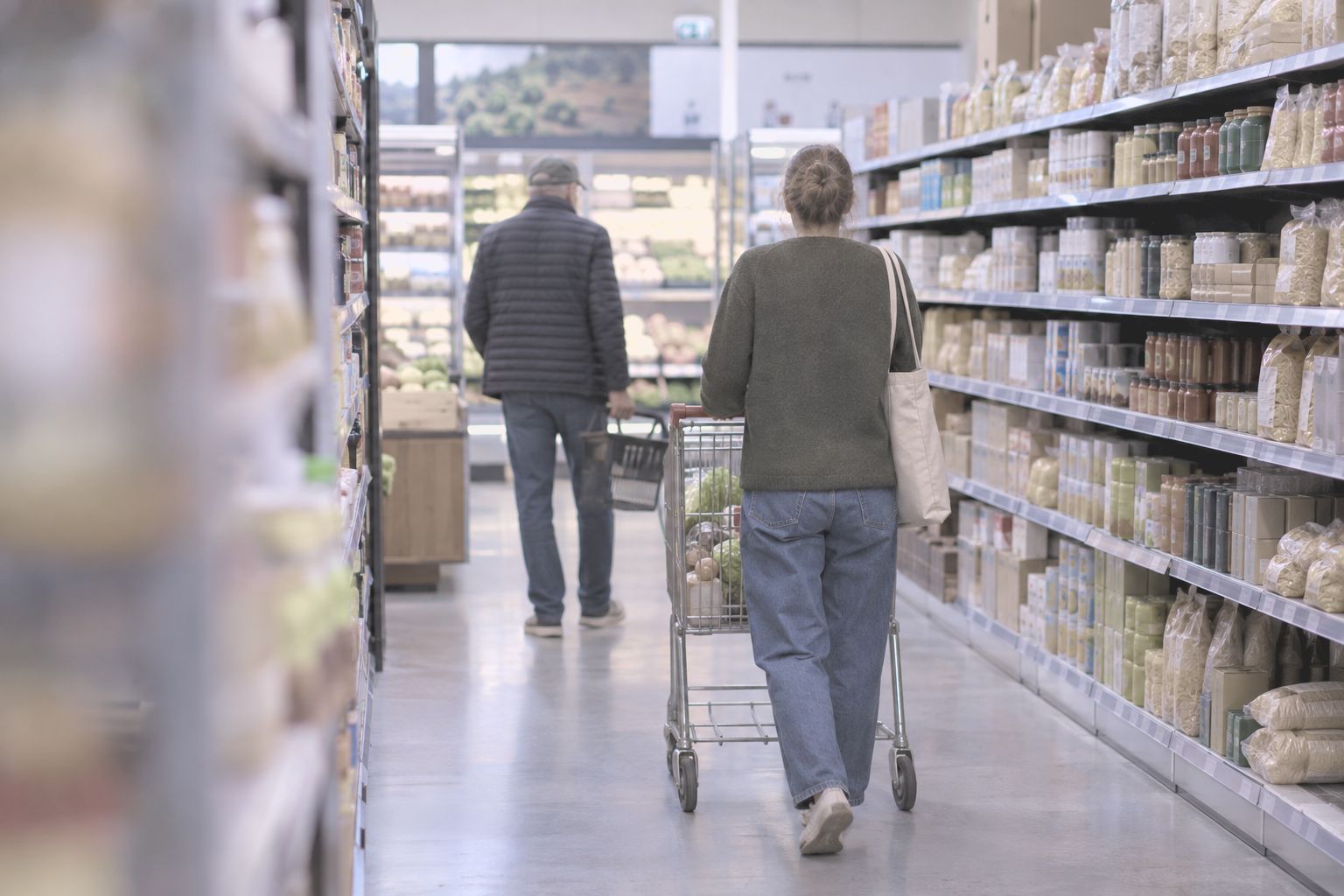 A shopper walking down a supermarket aisle