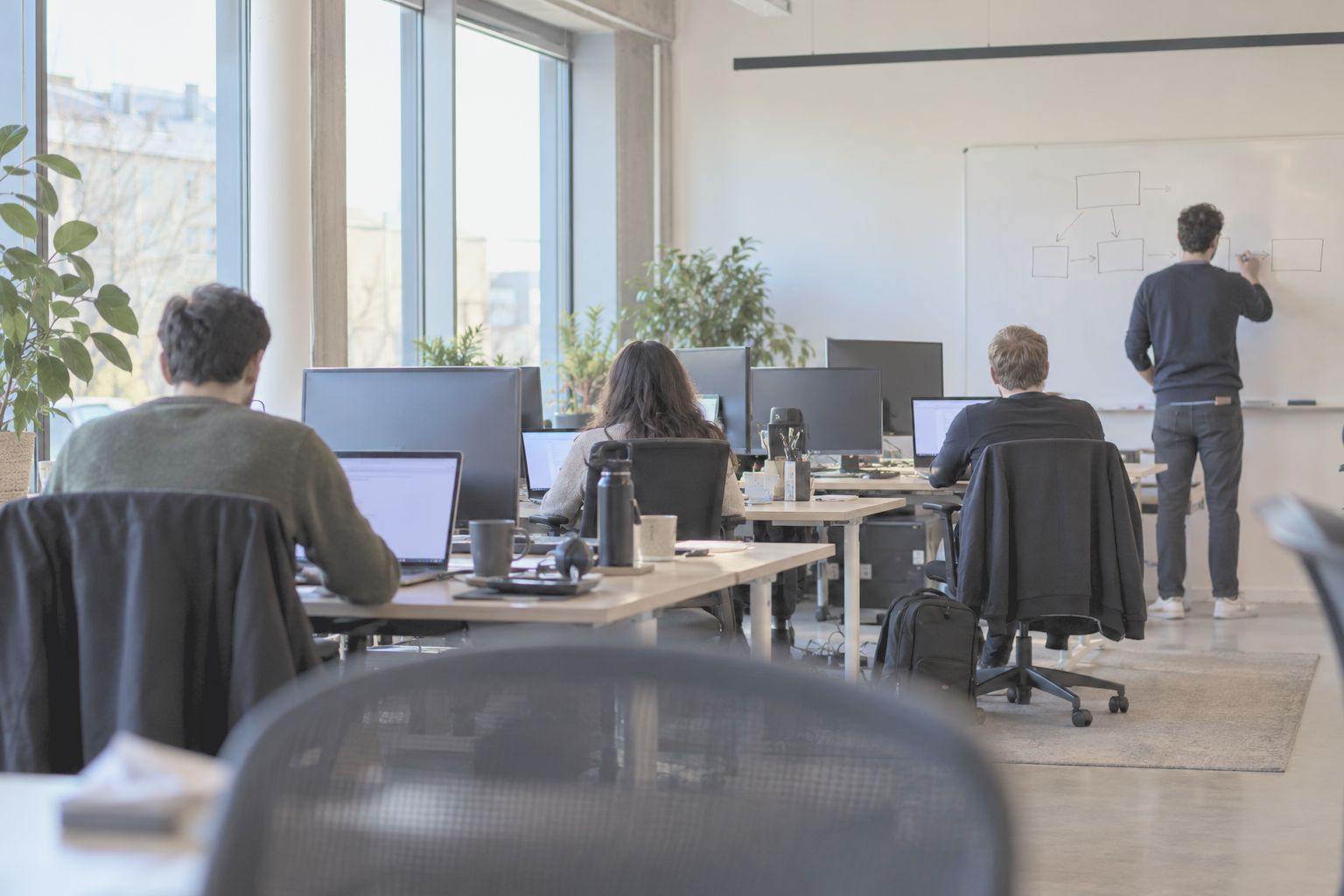 A software team at work in an open plan room, one person at a whiteboard