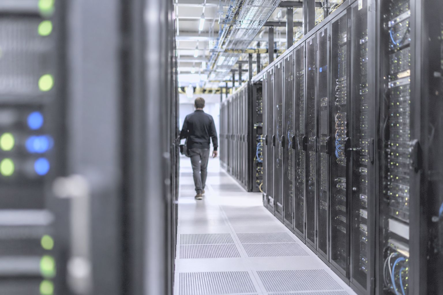 An engineer walking down a data centre aisle between rows of server racks
